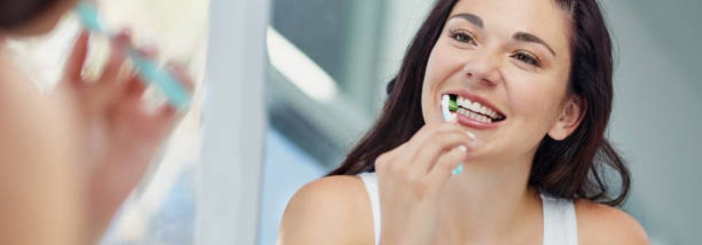 Shot of an attractive young woman brushing her teeth in the bathroom at home Shot of an attractive young woman brushing her teeth in the bathroom at home
