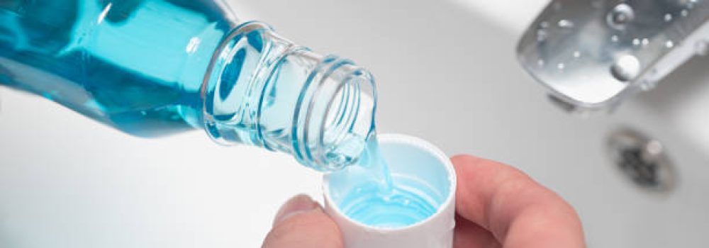 Hand of man Pouring Bottle Of Mouthwash Into Cap. Hand of man Pouring Bottle Of Mouthwash Into Cap.